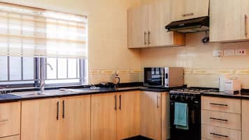 A kitchen with wooden cabinets, a gas stove, a microwave, and a sink.