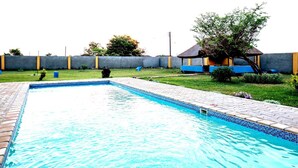 A rectangular swimming pool with a tiled edge, surrounded by a paved walkway. - Charming 2-bedroom house in marvelous Lusaka with AC (Lusaka)