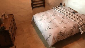 Un dormitorio con una cama, cabecera de madera, mesita de noche y lámpara.