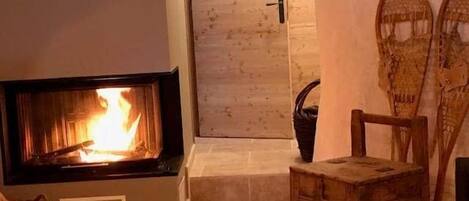 A fireplace with a visible fire, a wooden chest, and a wicker basket.