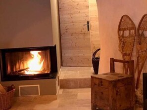 A fireplace with a visible fire, a wooden chest, and a wicker basket.