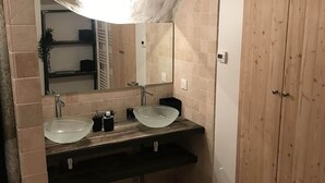 Un baño con dos lavamanos, un espejo grande y armarios de madera.