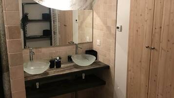 A bathroom with two sinks, a large mirror, and wooden cabinets.