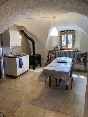 Una cucina accogliente con piano cottura integrato, un tavolo da pranzo con tovaglia fantasia e una finestra con soprammobili decorativi.