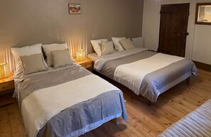 Camera da letto con due letti, pavimento in legno e lampade sui comodini.