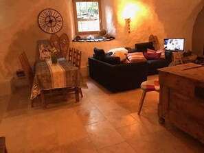 A cozy living room with a dining table, sofa, and a television.