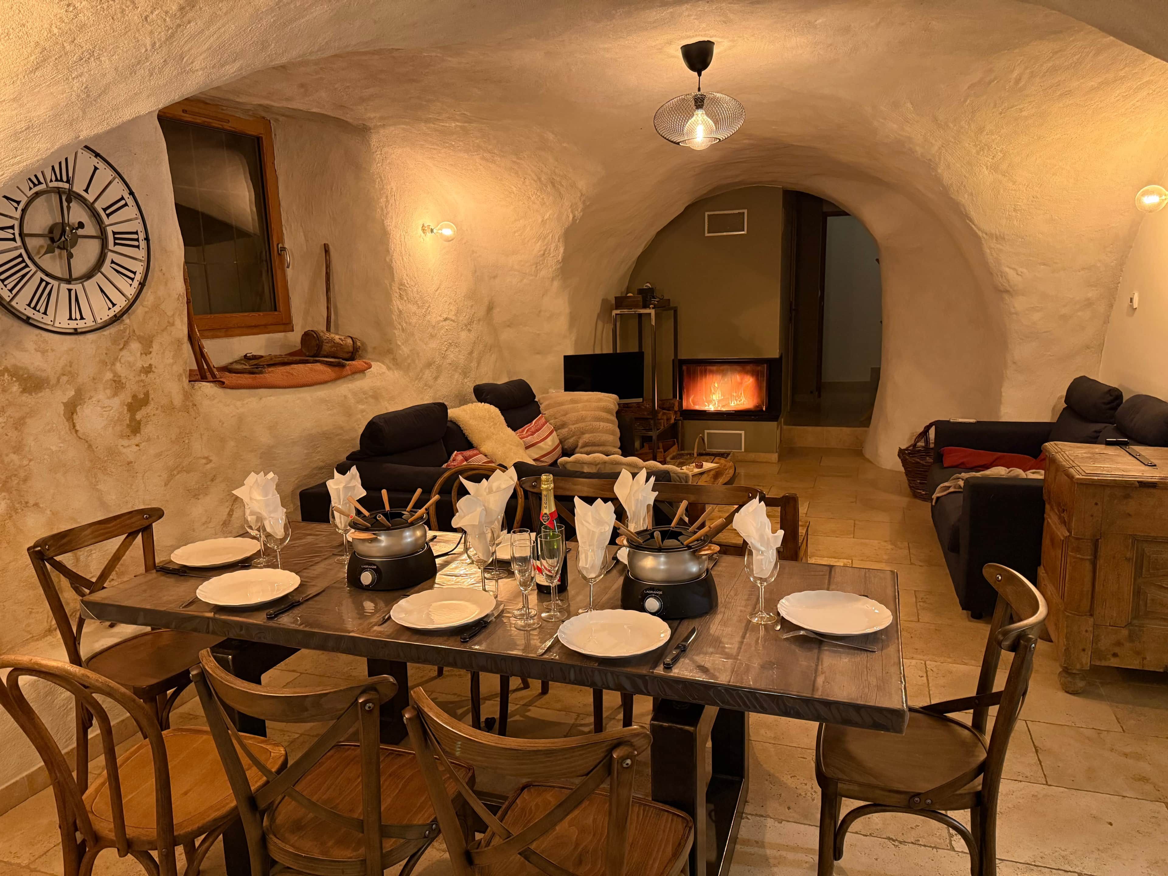 Un coin repas chaleureux, avec un mur en pierre rustique, une grande horloge et une cheminée.