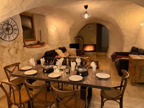 Un'accogliente zona pranzo con una parete in pietra rustica, un grande orologio e un camino.