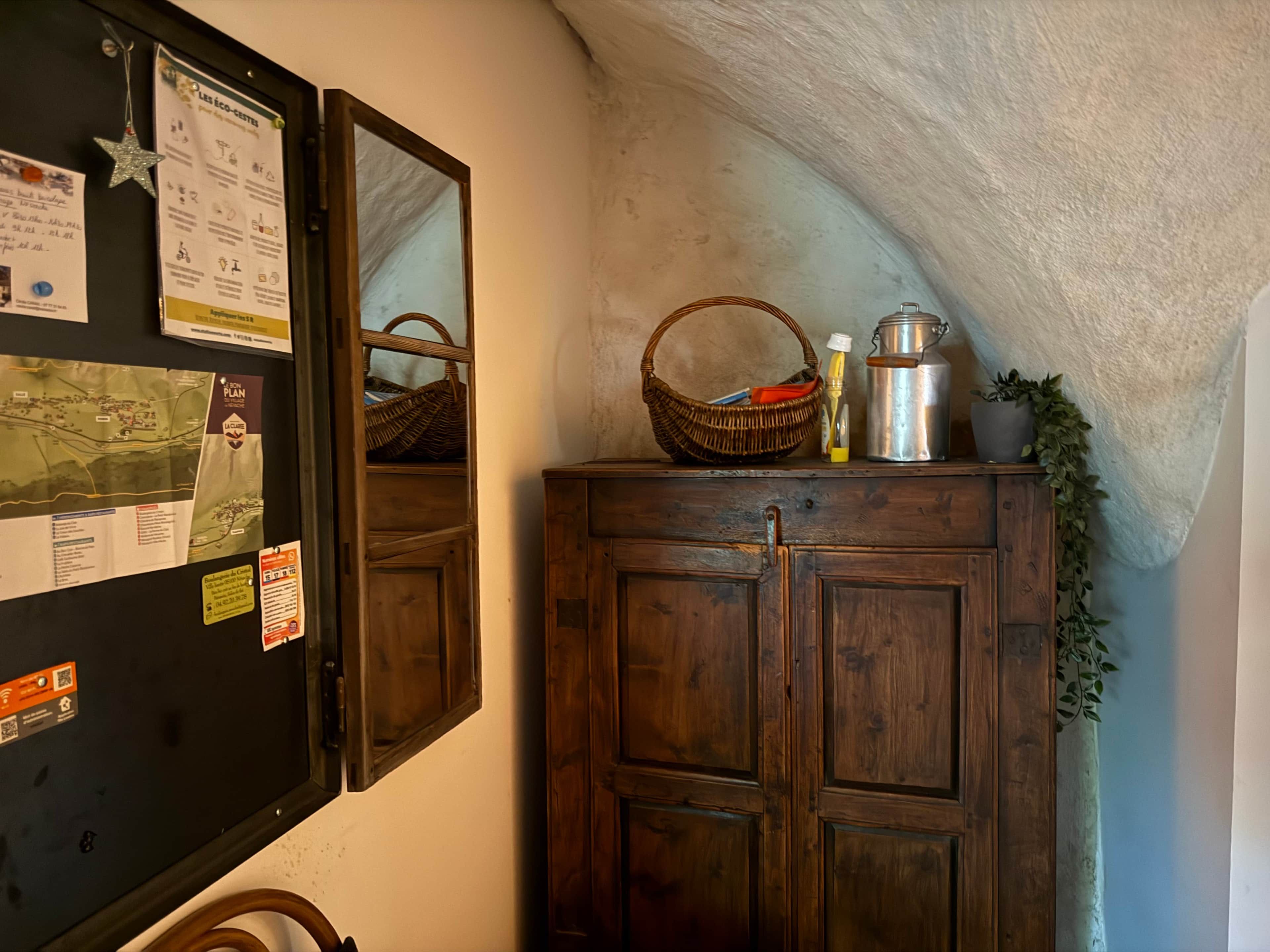 A wooden cabinet with a mirror, a map, and a basket on top.