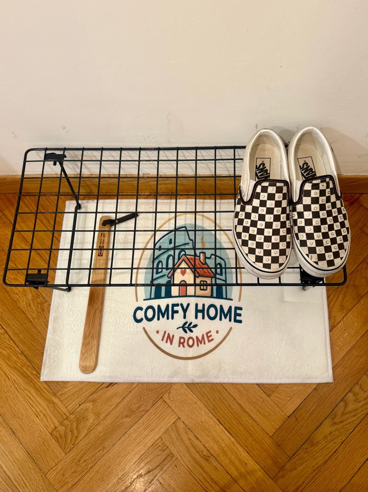 A pair of checkered shoes on a wire shelf, a wooden spoon, and a placemat with 'COMFY HOME IN ROME' text.