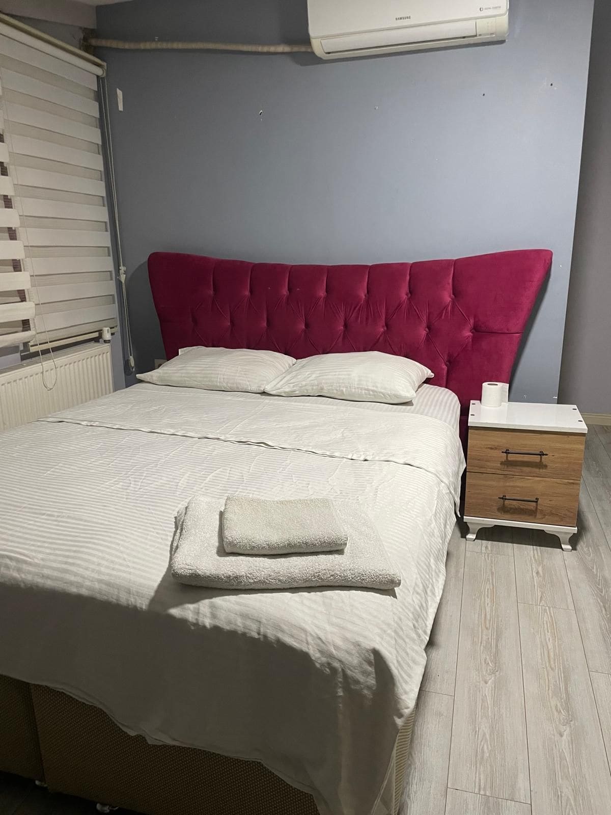Ein Schlafzimmer mit Bett, Nachttisch und Klimaanlage.