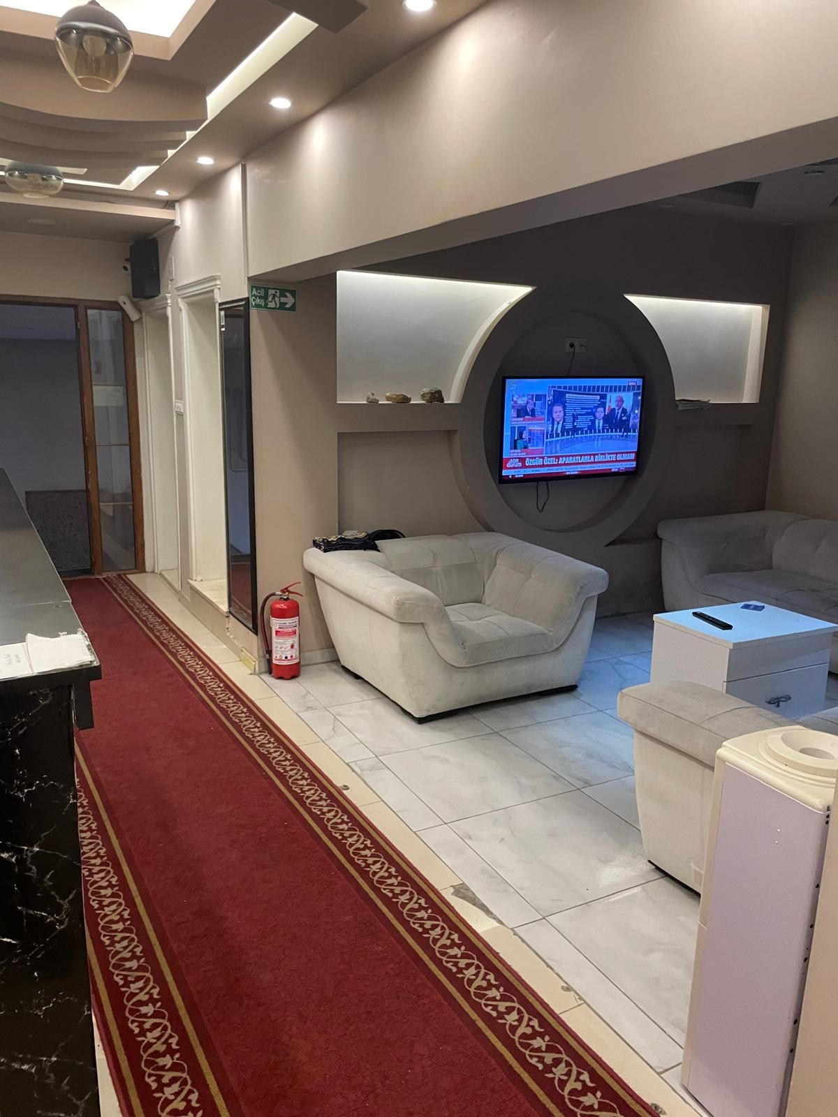 Une chambre moderne avec un téléviseur à écran plat fixé au mur, un canapé, une petite table et une moquette rouge.