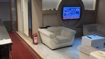 Une chambre moderne avec un téléviseur à écran plat fixé au mur, un canapé, une petite table et une moquette rouge.