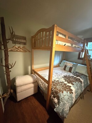 A bunk bed with a wooden frame, a hanging clothes rack, a small bench, and a decorative wall piece. - Charming 3-bedroom cabin in delightful Soda Springs getaway. Sorry no pets. (Soda Springs)