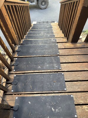 A wooden deck with a series of black metal steps leading to a vehicle. - Charming 3-bedroom cabin in delightful Soda Springs getaway. Sorry no pets. (Soda Springs)