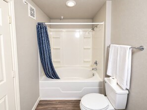A bathroom with a bathtub, toilet, and shower curtain. - Sleepover | Picturesque 1BD/1BA+Gym Corpus Christi (Corpus Christi)