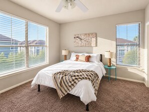 A bedroom with a bed, two bedside tables, a ceiling fan, and a window with blinds. - Sleepover | Picturesque 1BD/1BA+Gym Corpus Christi (Corpus Christi)