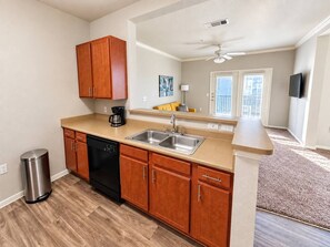 A kitchen with wooden cabinets, a dishwasher, a coffee maker, and a sink.