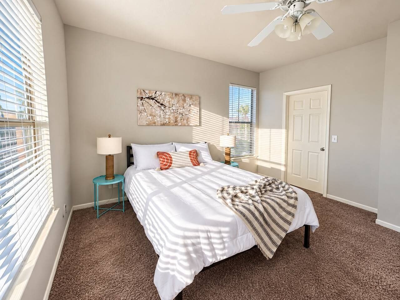 A bedroom with a bed, nightstands, a ceiling fan, and a door.