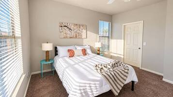 A bedroom with a bed, nightstands, a ceiling fan, and a door.