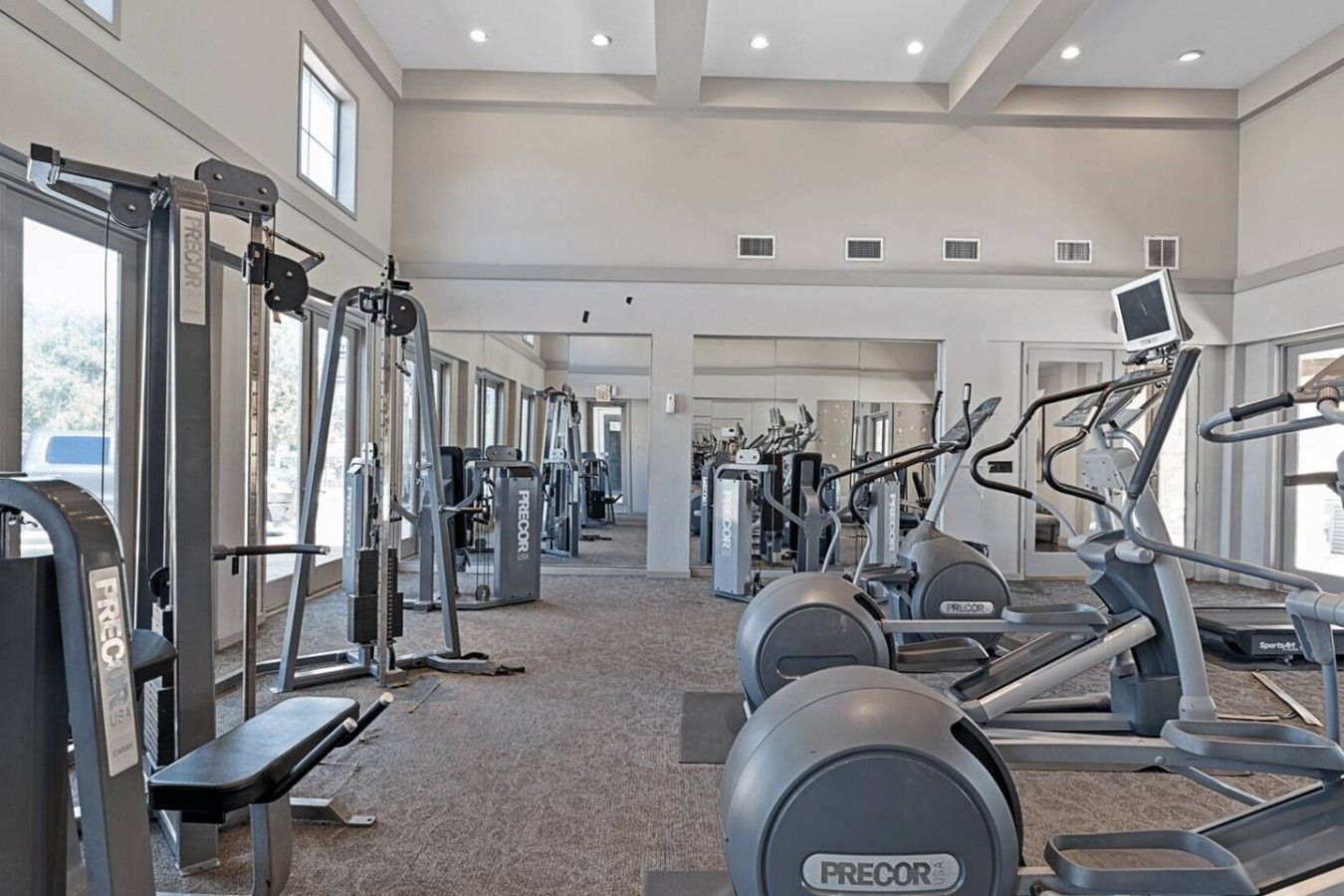 A gym with various exercise equipment, including treadmills and weight machines, arranged in a spacious layout.