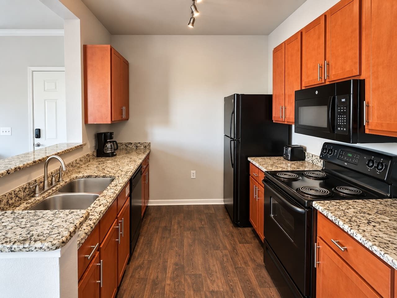 A kitchen with granite countertops, a black refrigerator, a microwave, and a stove.