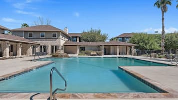 A swimming pool with a no diving sign, surrounded by houses with stone facades and a clear blue sky.
