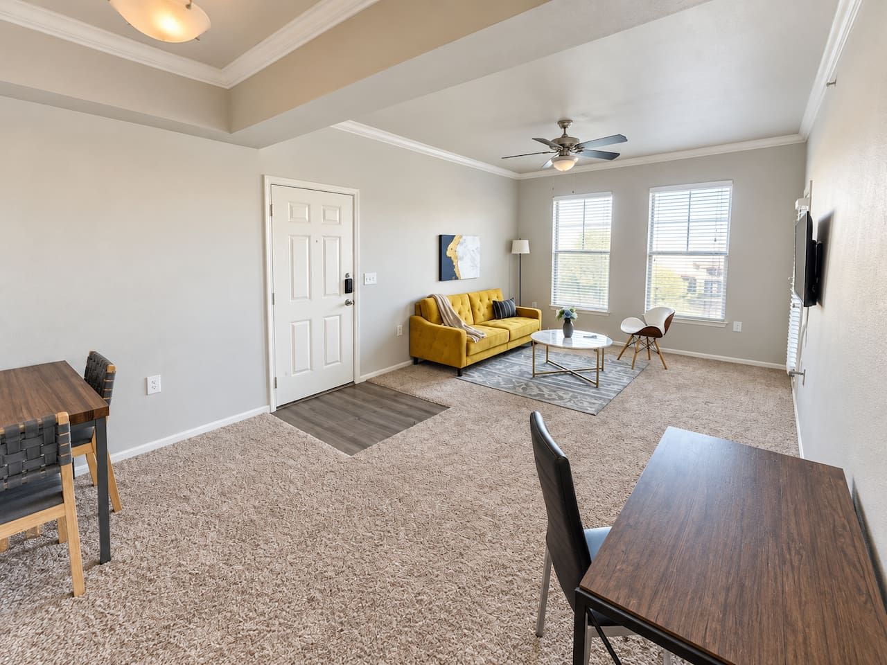 A spacious living area with a dining table, sofa, and a ceiling fan.