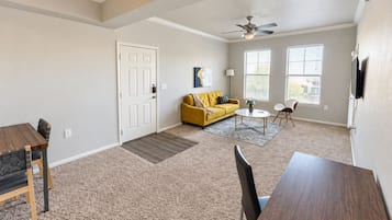 A spacious living area with a dining table, sofa, and a ceiling fan.
