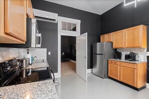 Une cuisine moderne avec un mur noir, des armoires en bois, des appareils en acier inoxydable et un comptoir en granit.