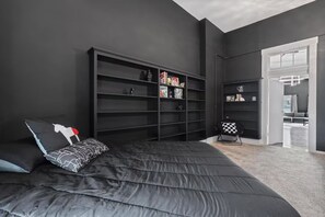 Une chambre avec un grand lit, une bibliothèque et un bureau.