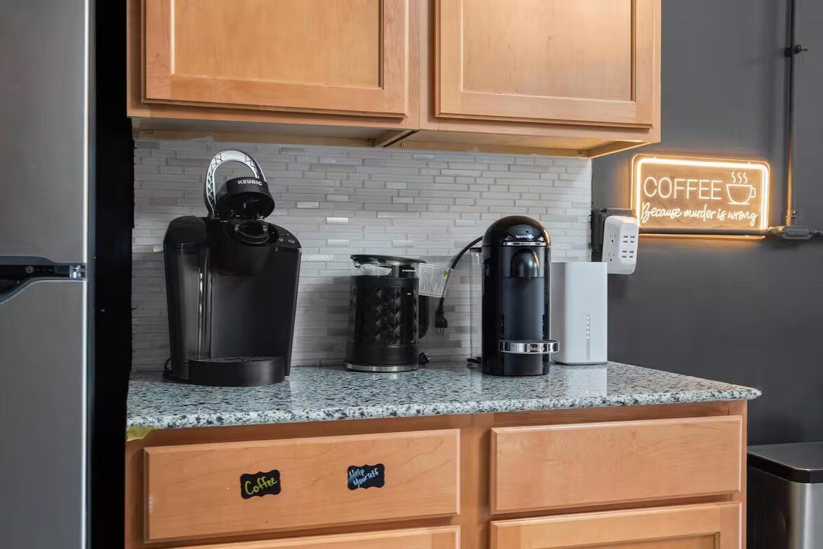 Eine Küche mit Holzausstattung, einer Kaffeemaschine, einem Wasserkocher und einer Kaffeemaschine auf der Arbeitsplatte.