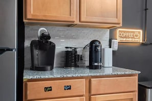 Una cocina con armarios de madera, una cafetera, un hervidor y una máquina de café en la encimera.