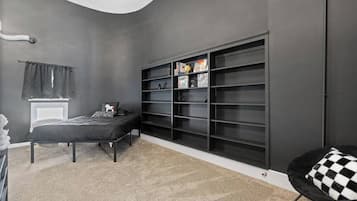A bedroom with a bed, a large black shelving unit, and a checkered chair.