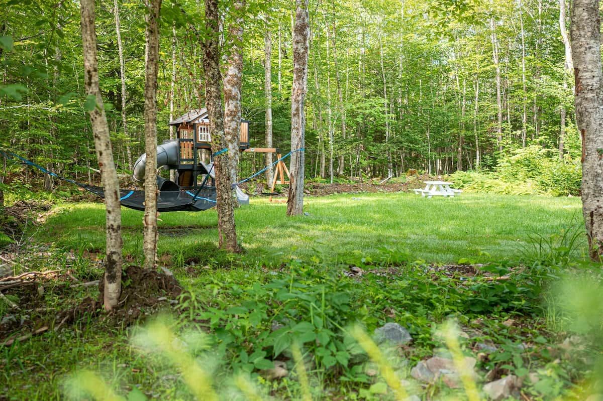 Ein bewaldetes Gebiet mit Spielplatz, Picknicktisch und Hängematte.
