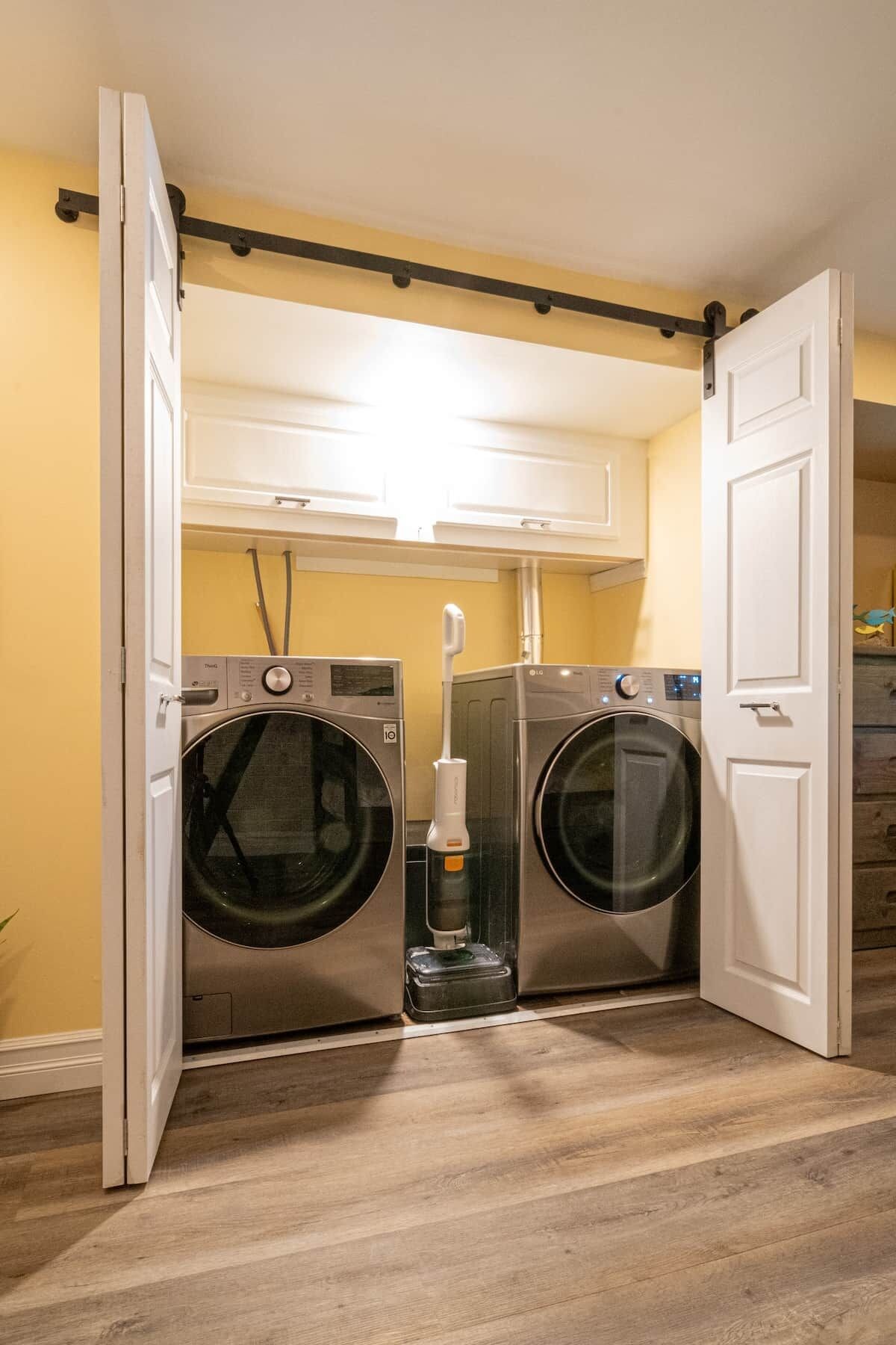 A laundry room with two front-loading washing machines, a dryer, and a water heater.