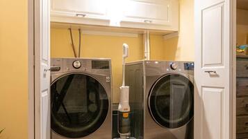 A laundry room with two front-loading washing machines, a dryer, and a water heater.