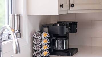 A kitchen with white cabinets, a coffee maker, and a coffee pod holder.