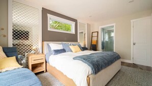 Une chambre à coucher avec un lit, des tables de chevet, une commode, une chaise et une fenêtre.