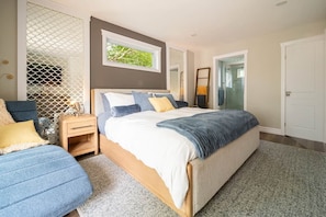 Quarto com cama, mesas de cabeceira, cadeira e janela.