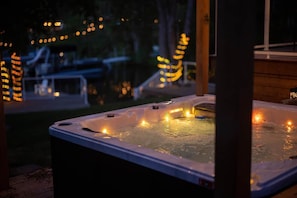 Uma banheira de hidromassagem com vista para um espaço de deck, rodeado por luzes de fada.
