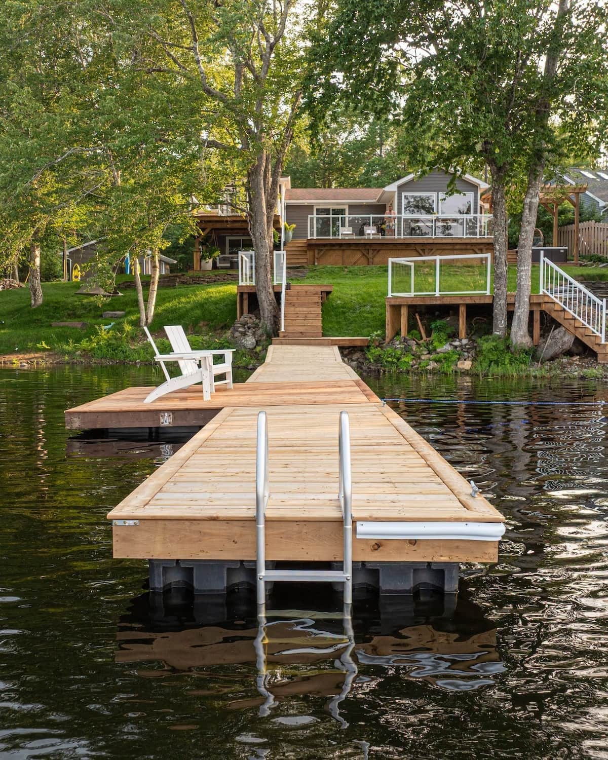 A wooden dock leading to a house with a deck and a staircase.