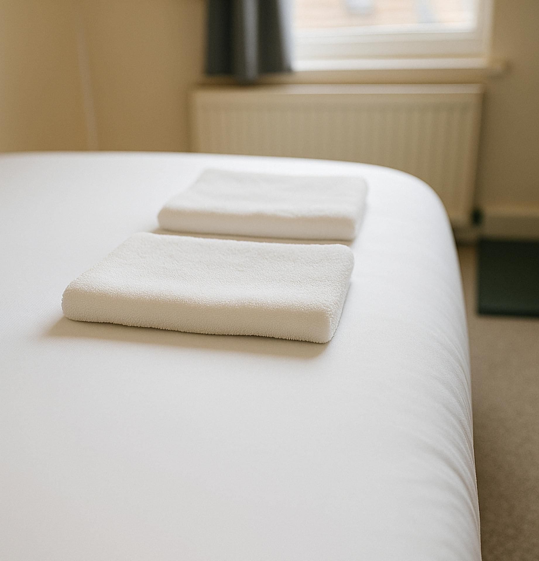 Ein Bett mit zwei ordentlich gefalteten weißen Handtüchern.
