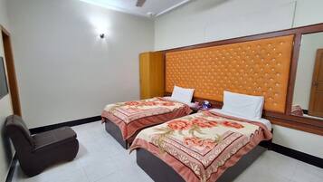 Habitación de hotel con dos camas, ventilador de techo y una silla.