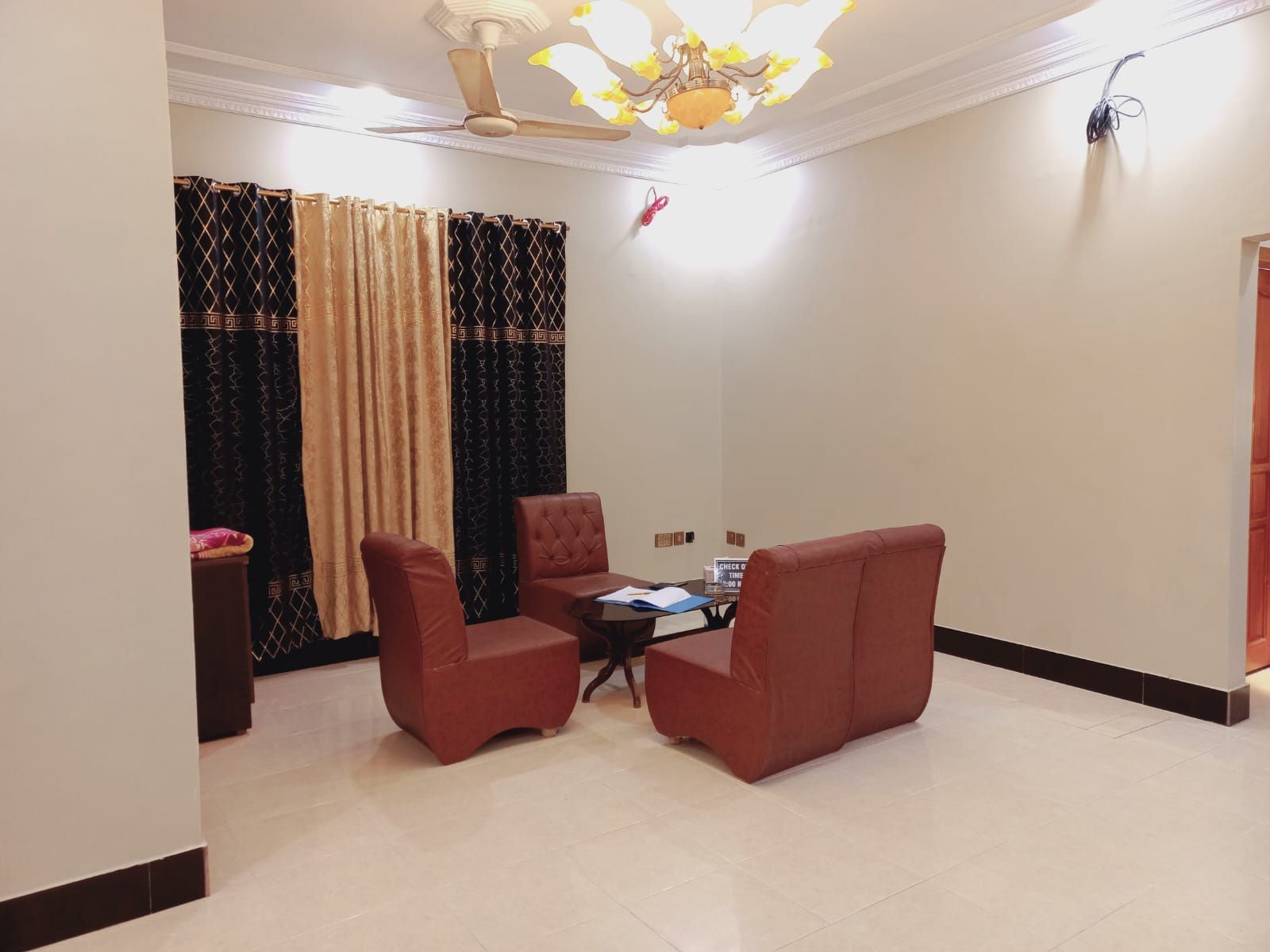 A room with a ceiling fan, a chandelier, a table with chairs, and a window with curtains.
