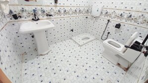A bathroom with a white sink, toilet, and shower. The floor has a diamond pattern. - BNB Rose Palace Lodge Family  (Karachi)