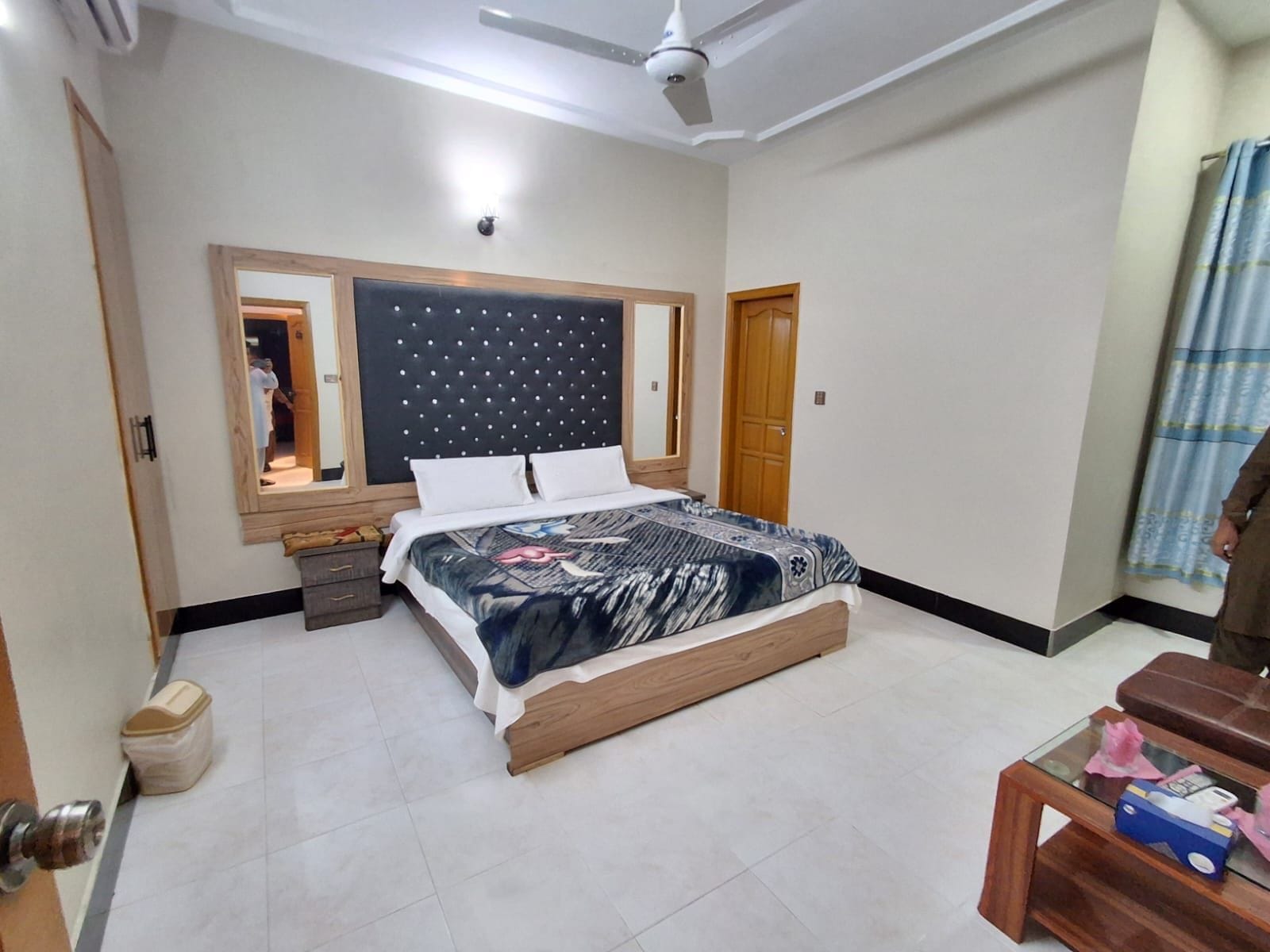 A bedroom with a bed, bedside tables, a ceiling fan, and a window with curtains.