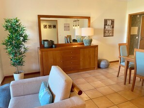 Una sala de estar con un sofá, una mesa de comedor con sillas, un mueble de madera y un espejo grande.