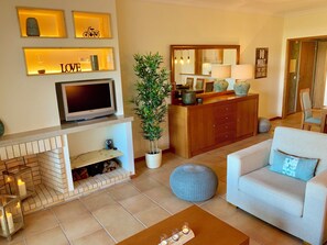 Ein Wohnzimmer mit Kamin, Fernseher, Sofa und Essbereich mit Spiegel und Dekoration.