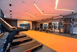 Un gimnasio moderno con cintas de correr, máquinas de pesas y un espejo grande.
